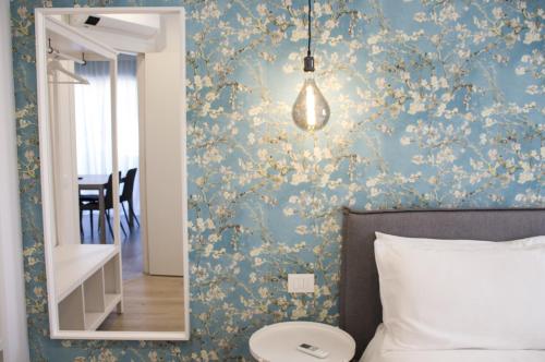 um quarto com paredes azuis, papel de parede floral e um espelho. em Bloom Apartments em Trento