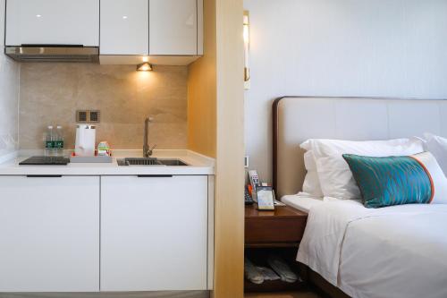 a bedroom with a bed and a kitchen with a sink at Jinling Funhome Hotel Nanjing Jiulong Lake - Nanjing South Railway Station in Nanjing