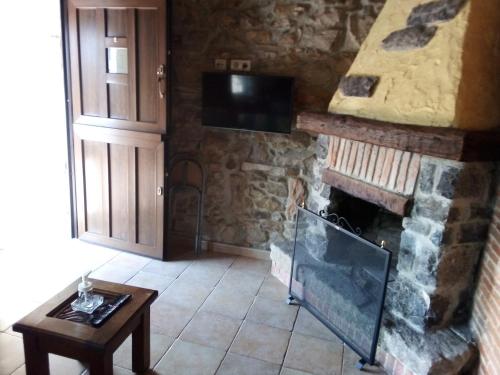 sala de estar con chimenea de piedra y TV en Las Cabañas de Pimiango, en Colombres