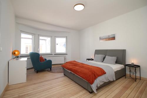 1 dormitorio con 1 cama y 1 silla azul en Appart Nicolas, en Eupen