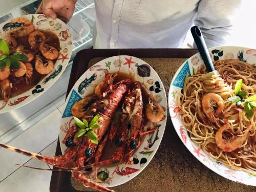 two plates of food with shrimp and pasta on a table at Aigeiros Apartments & restaurant in Skala Mistegnon