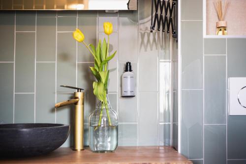 a bathroom with a sink and a vase with yellow flowers at Boutique Hotel Enkhuizen in Enkhuizen