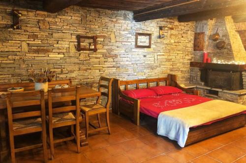 a bedroom with a bed and a table and a brick wall at Monolocale rustico di montagna in Antey-Saint-André