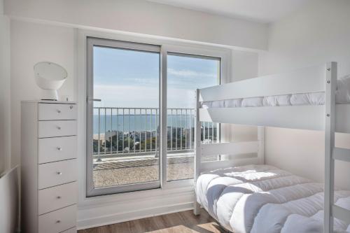 une chambre blanche avec un lit et une grande fenêtre dans l'établissement 350m plage, vue incroyable sur la baie de la Baule, à Pornichet