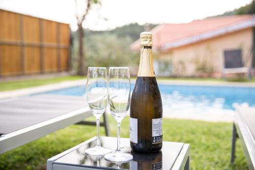 a bottle of champagne and two wine glasses on a table at Casa da Pontelha by Gerês Casas in Terras de Bouro