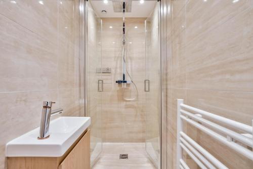 La salle de bains est pourvue d'une douche et d'un lavabo blanc. dans l'établissement 102 - Urban Opera Picasso, à Paris