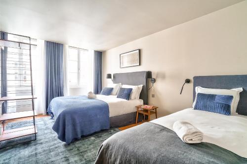 a hotel room with two beds and a window at 134 - Urban Gorgeous Flat in Montorgueil in Paris