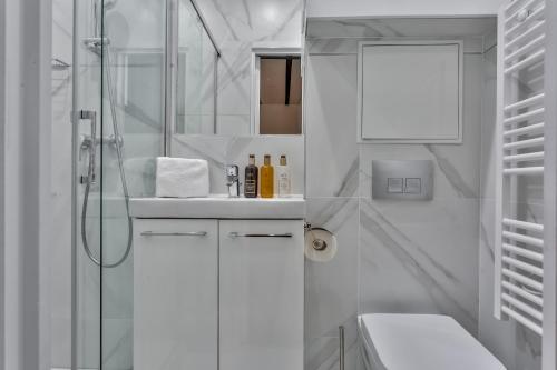 biała łazienka z prysznicem i umywalką w obiekcie 114 - Urban Saint Denis Couture w Paryżu