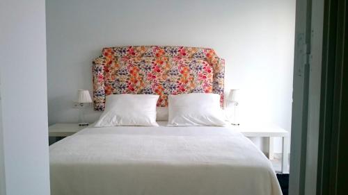 1 dormitorio con cama blanca y cabecero de flores en One bedroom apartement with sea view furnished terrace and wifi at El Puerto de Santa Maria 2 km away from the beach, en El Puerto de Santa María