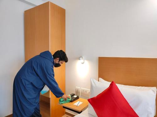 a man using a phone in a hotel room at Kanak Beacon Hotel - Ashram Road Ahmedabad in Ahmedabad