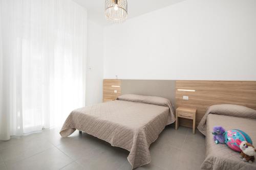 a bedroom with two beds and a stuffed animal on a chair at Residence OndaMare in Cervia
