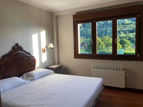 a bedroom with a bed and a large window at Arroes Village And Pool - Villa con piscina privada in Villaviciosa