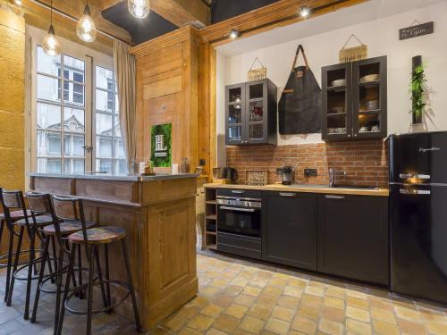 a kitchen with black appliances and a bar with stools at HOST INN - CŒUR VIEUX LYON & SPA in Lyon