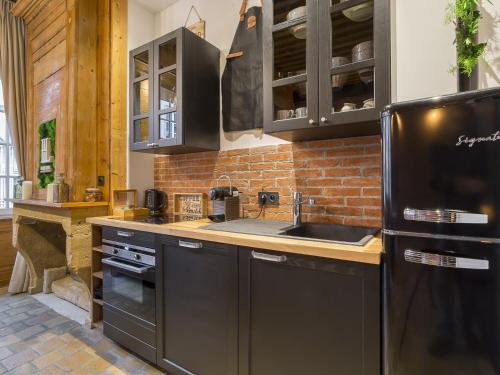 a kitchen with black appliances and a brick wall at HOST INN - CŒUR VIEUX LYON & SPA in Lyon