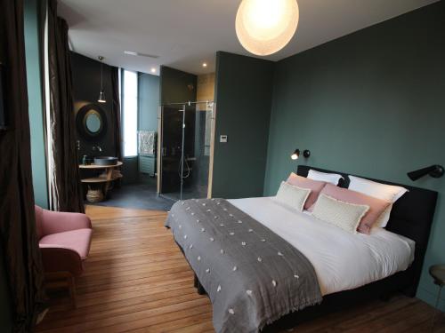 um quarto com uma cama grande e uma cadeira rosa em B&B L'Escapade Bordelaise - Côté Jardin em Bordeaux