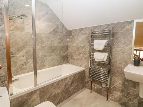 un baño con bañera y lavabo en The Haybarn, en Ashbourne