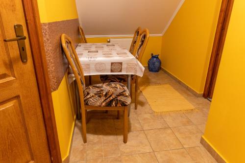 a small table and chairs in a room with yellow walls at Gál Apartmanház in Harkány