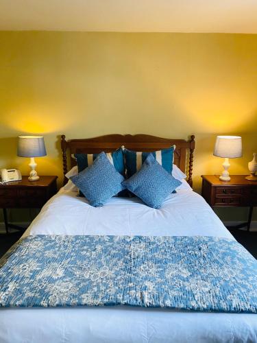 a bedroom with a bed with blue pillows and two lamps at Softleys in Market Bosworth
