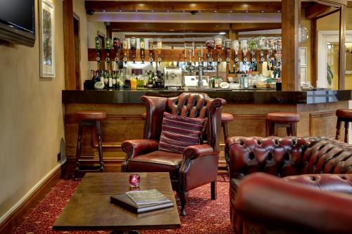 - un bar avec deux fauteuils en cuir et une table dans l'établissement Bury Ramsbottom Old Mill Hotel and Leisure Club, à Ramsbottom