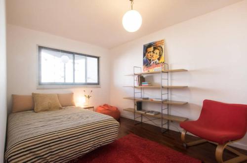 a bedroom with a bed and a red chair at Apartamento Centro & Chic in Alicante