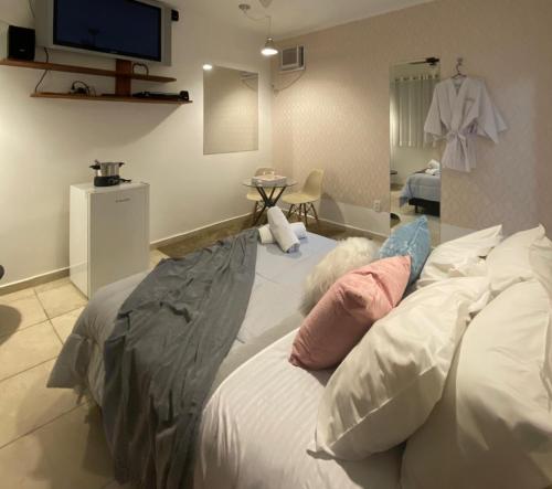 um quarto com uma cama com almofadas e uma televisão em Hotel ITR-SPA em Itupeva