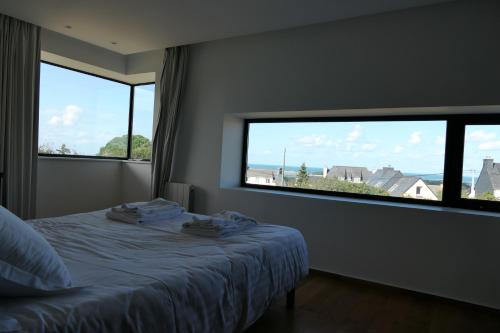 - une chambre avec un lit et 2 grandes fenêtres dans l'établissement Villa Dremmwel - Villa d'architecte vue mer panoramique, à Penvénan