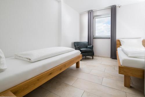 a bedroom with two beds and a chair and a window at Apartmenthaus Aulendorf in Aulendorf