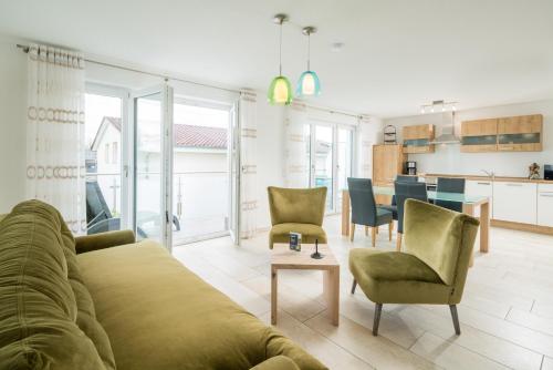 a living room with a couch and chairs and a kitchen at Apartmenthaus Aulendorf in Aulendorf
