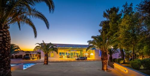 a building with palm trees in front of it at President Hotel, Valamar Collection in Dubrovnik