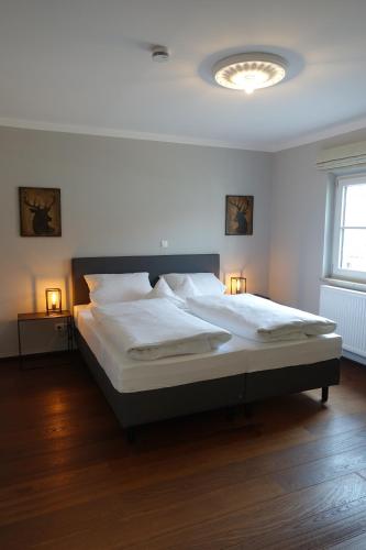 a bedroom with a large white bed with two lamps at Hotel zur Sonne in Rimsting