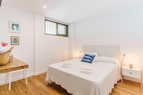 a white bedroom with a bed and a desk at Balaixa 8 in Port de Pollensa