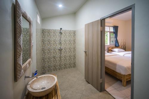 a bathroom with a sink and a bed and a shower at Endless Summer Surf Camp Kuta in Kuta