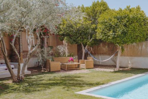 un patio trasero con una hamaca, árboles y una piscina en Tagadert Lodge en Oumnas