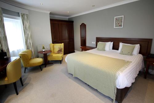 a bedroom with a bed and a desk and chairs at Mercure Gloucester Bowden Hall Hotel in Gloucester