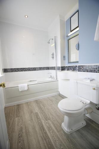 a white bathroom with a toilet and a bath tub at Mercure Gloucester Bowden Hall Hotel in Gloucester