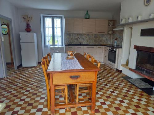 une cuisine avec une table avec des chaises et un réfrigérateur dans l'établissement Gîte de Bazeille, à Saint-Avit-Sénieur