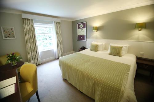 a hotel room with a bed and a yellow chair at Mercure Gloucester Bowden Hall Hotel in Gloucester
