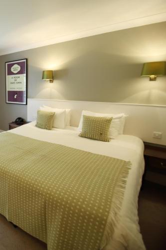 a bedroom with a large bed with two pillows at Mercure Gloucester Bowden Hall Hotel in Gloucester
