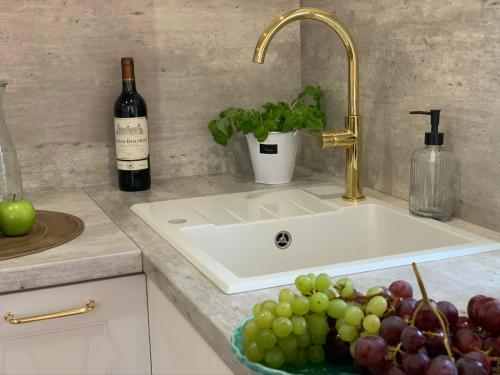 - un lavabo avec un bol de raisin et une bouteille de vin dans l'établissement Apartamenty Kamienica Arte 4, à Ustka
