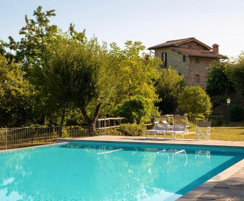 a swimming pool with two chairs and a house at Fattorie di Celli in Poppi