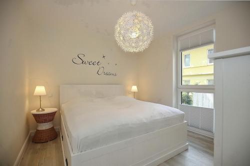 a bedroom with a white bed and a chandelier at Strandvilla Scholle - Dorsch Wohnung 02 in Boltenhagen