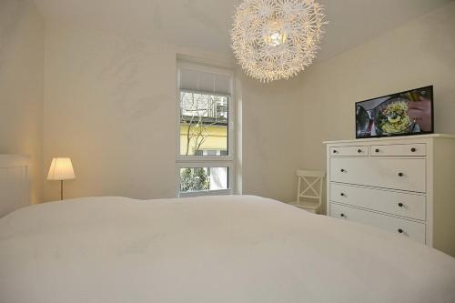 una camera con letto bianco e lampadario pendente di Strandvilla Scholle - Makrele Wohnung 04 a Boltenhagen