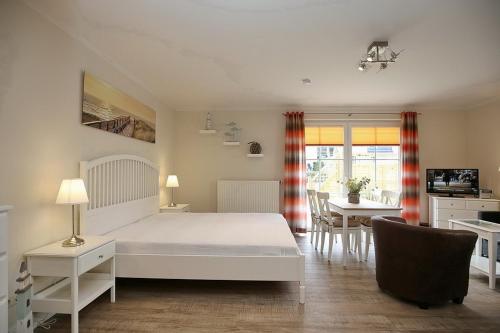 a bedroom with a white bed and a dining room at Strandvilla Krabbe Wohnung 08 in Boltenhagen