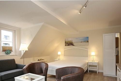 a bedroom with a bed and two chairs and a couch at Strandvilla Krabbe Wohnung 12 in Boltenhagen