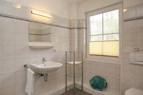 a white bathroom with a sink and a window at Strandvilla Krabbe Wohnung 12 in Boltenhagen