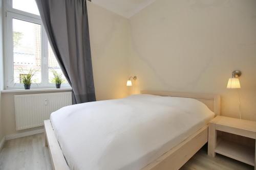 a white bed in a room with a window at Villa Triton Wohnung 01 in Boltenhagen