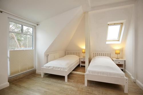 2 bedden in een witte kamer met een raam bij Villa Triton Wohnung 05 in Boltenhagen