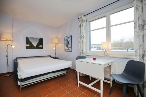 a bedroom with a bed and a desk and a window at Dünenblick Wohnung 49 in Boltenhagen