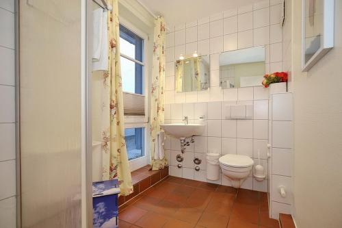 a bathroom with a toilet and a sink and a window at Dünenblick Wohnung 49 in Boltenhagen