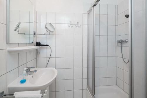 a white bathroom with a sink and a shower at Sünnslag Wohnung 029 in Boltenhagen